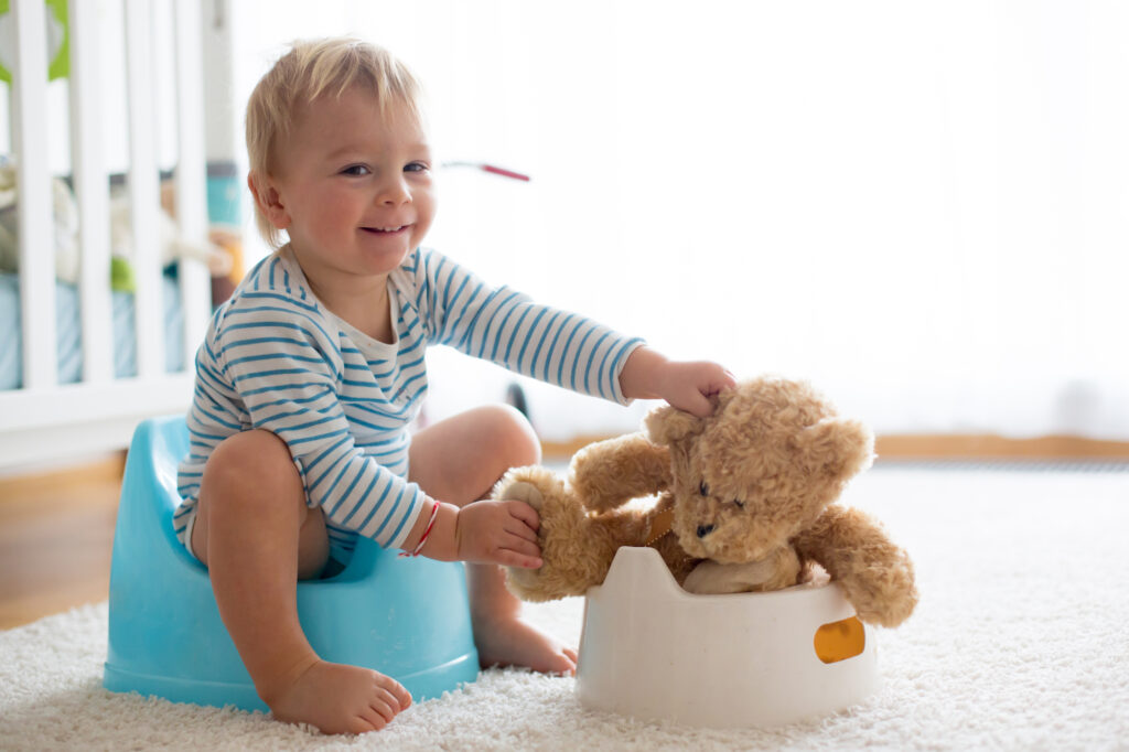 Little boy potty training with teddy bear